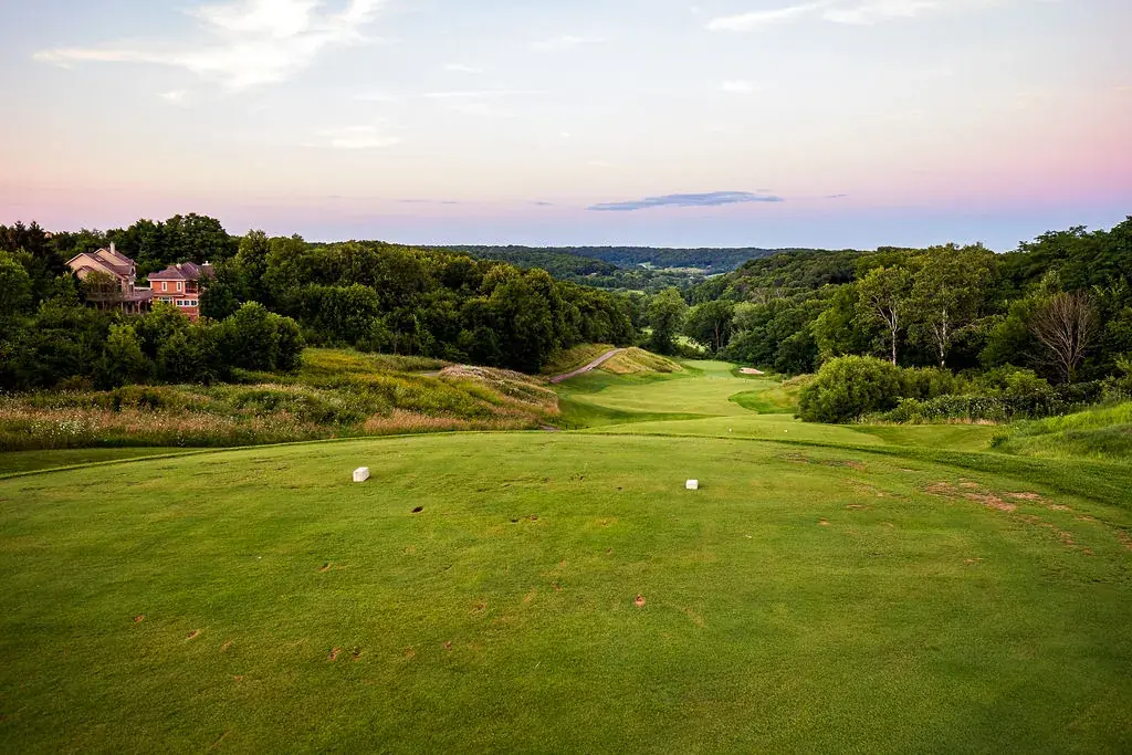 A tee box looking down a fairway into wooded hills