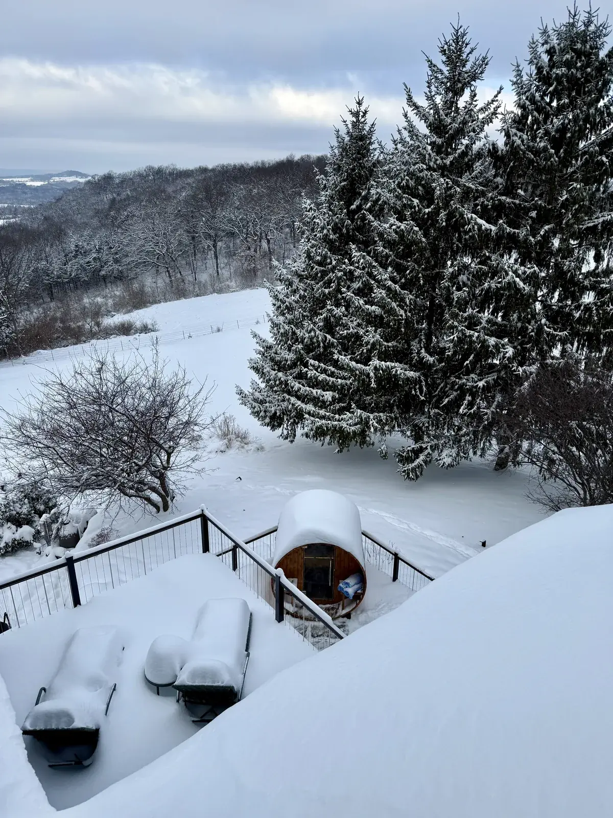 The cedar barrel sauna on the deck after a snowfall, looking over the valley