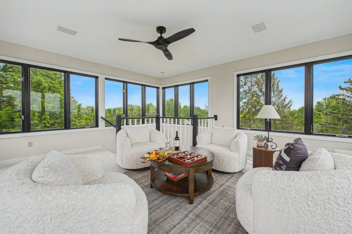 The tower room: white lounge chairs in a ring of windows above the treeline
